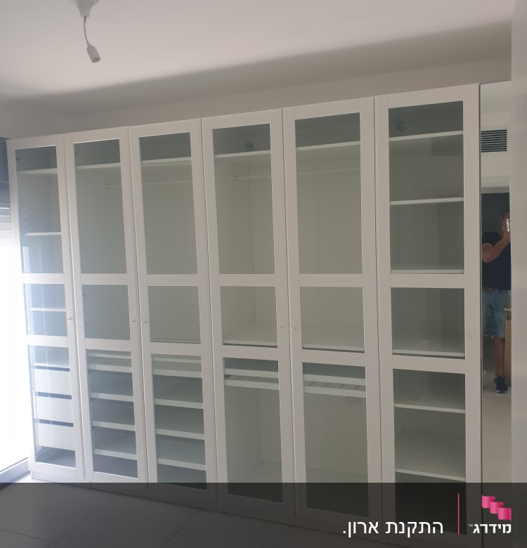 ארון לבן עם דלתות זכוכית ומדפים פנימיים